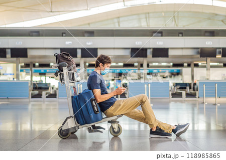 Man in mask at empty airport at check in in coronavirus quarantine isolation, returning home, flight cancellation, pandemic infection worldwide spread, travel restrictions and border shutdown 118985865