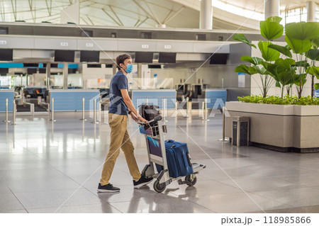 Man in mask at empty airport at check in in coronavirus quarantine isolation, returning home, flight cancellation, pandemic infection worldwide spread, travel restrictions and border shutdown Man in mask at empty airport at check in in coronavirus quarantine isolation, returning home, flight cancellation, pandemic infection worldwide spread, travel restrictions and border shutdown 118985866