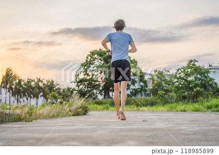 A man runner is engaged in jogging on a concrete path without shoes, without sneakers, for health 118985899