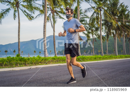 Runner wearing medical mask, Coronavirus pandemic Covid-19. Sport, Active life in quarantine surgical sterilizing face mask protection. Outdoor run on athletics track in Corona Outbreak 118985969