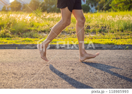 A man runner is engaged in jogging on the asphalt without shoes, without sneakers, for health A man runner is engaged in jogging on the asphalt without shoes, without sneakers, for health 118985993