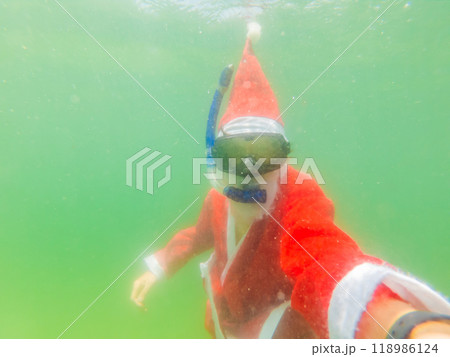 Santa claus is snorkeling underwater - christmas or happy new year concept. Christmas in the tropics after quarantine was lifted Coronovirus COVID 19 concept 118986124