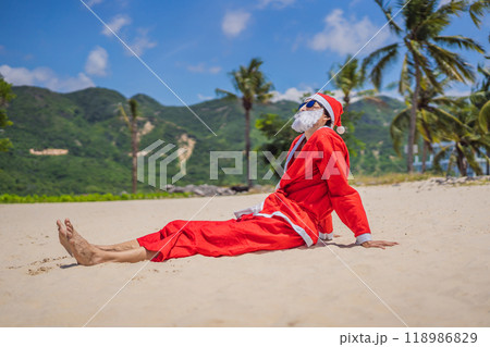 Santa Claus relaxing on sea beach - christmas or happy new year concept. Christmas in the tropics after quarantine was lifted Coronovirus COVID 19 concept Santa Claus relaxing on sea beach - christmas or happy new year concept. Christmas in the tropics after quarantine was lifted Coronovirus COVID 19 concept 118986829