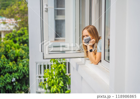 Extremly tired woman looking out the window, home alone. self-isolation at home, quarantine due to pandemic COVID 19. Mental health problems in self-isolation at home, quarantine, isolation, stay at 118986865
