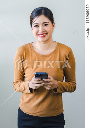 Confident asian woman with friendly smile stands with hand holding smartphone isolated on white background. 118986959