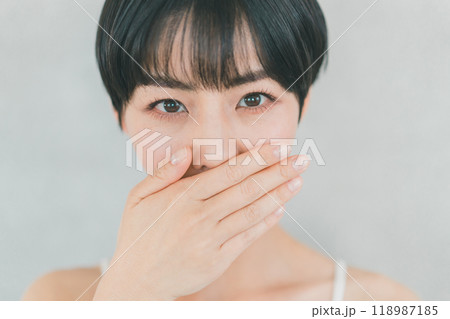 口元を手で隠す若い女性 118987185