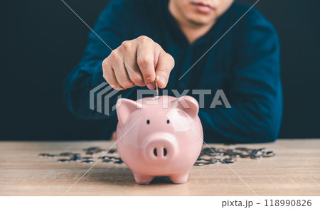 Man put money coin into pink piggy bank for saving money wealth, The concept of saving money or investment. Man put money coin into pink piggy bank for saving money wealth, The concept of saving money or investment. 118990826