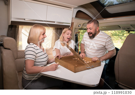 A family of three is playing a board game while sitting in a motorhome A family of three is playing a board game while sitting in a motorhome 118991830