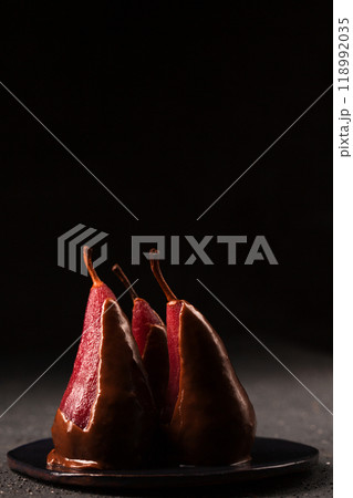 French dessert spiced pear in wine with chocolate glaze, low key photo French dessert spiced pear in wine with chocolate glaze, low key photo 118992035
