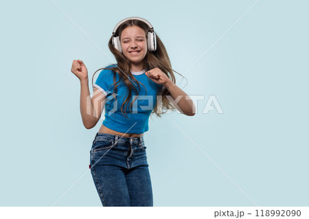 Girl wearing headphones dances joyfully while listening to music. 118992090