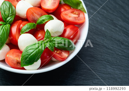 Basil leaves , cherry tomatoes and mozzarella cheese . In bowl food photography 118992293