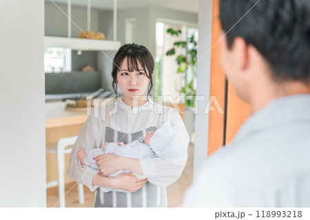帰宅した夫を不機嫌な顔で見つめる赤ちゃんを抱いた妻・若いアジア人女性 帰宅した夫を不機嫌な顔で見つめる赤ちゃんを抱いた妻・若いアジア人女性 118993218