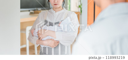帰宅した夫を不機嫌な顔で見つめる赤ちゃんを抱いた妻・若いアジア人女性 帰宅した夫を不機嫌な顔で見つめる赤ちゃんを抱いた妻・若いアジア人女性 118993219