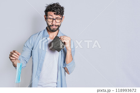 People deciding which surgical mask to wear, Person deciding to wear a medical mask in an isolated context, Isolated man deciding which medical mask to wear 118993672