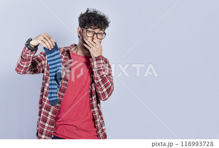 Handsome man with a smelly sock in his hand holding his nose isolated. Person with a stinky sock in his hand, concept of smelly socks and uncleanliness 118993728