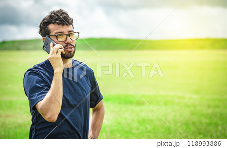 Man calling by cell phone, young man in the field calling by cell phone Man calling by cell phone, young man in the field calling by cell phone 118993886