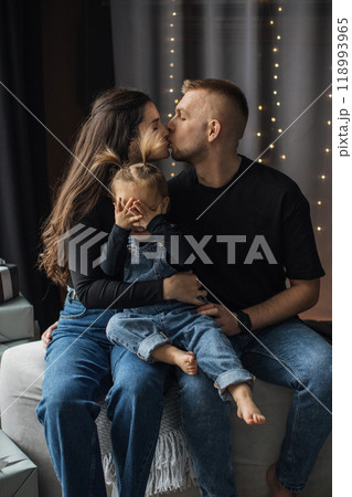 Loving family moment with parents kissing child Loving family moment with parents kissing child 118993965