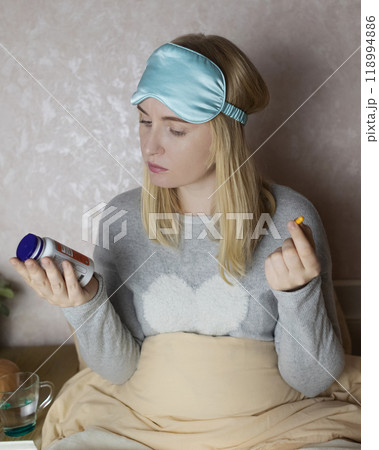A woman cannot fall asleep and wants to drink a capsule with melatonin, a sleeping pill. Manifestations of jitlag or insomnia. Regulation of biological rhythms A woman cannot fall asleep and wants to drink a capsule with melatonin, a sleeping pill. Manifestations of jitlag or insomnia. Regulation of biological rhythms 118994886