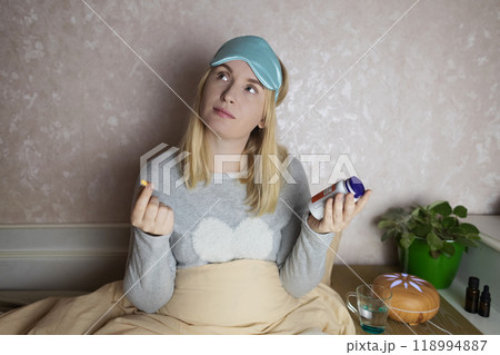 A woman cannot fall asleep and wants to drink a capsule with melatonin, a sleeping pill. Manifestations of jitlag or insomnia. Regulation of biological rhythms A woman cannot fall asleep and wants to drink a capsule with melatonin, a sleeping pill. Manifestations of jitlag or insomnia. Regulation of biological rhythms 118994887