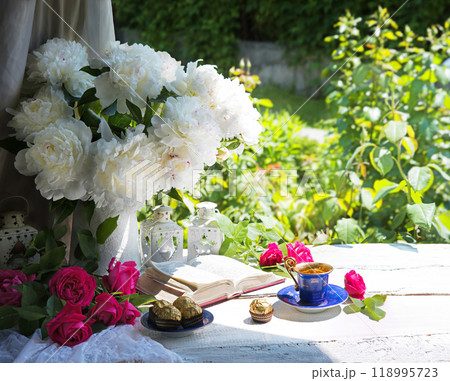Bible and a bouquet of peonies on a table in the garden 118995723