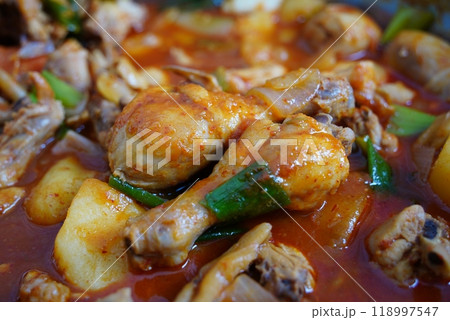Spicy Braised Chicken dish is made by boiling chicken, potatoes, and onions in a sauce 118997547