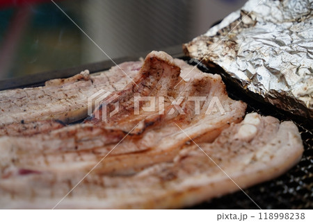Close-up of pork belly being grilled on a charcoal grill. Close-up of pork belly being grilled on a charcoal grill. 118998238