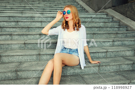 Beautiful young woman model sitting on the stairs on city street 118998927