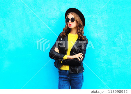 Fashion pretty woman model in black rock style clothes over colorful blue background Fashion pretty woman model in black rock style clothes over colorful blue background 118998952