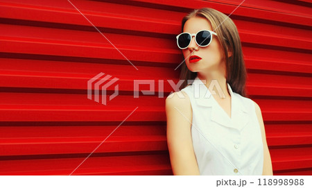 Portrait of stylish young woman model posing wearing sunglasses on red background 118998988