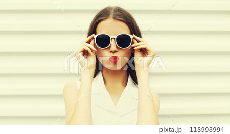 Portrait of stylish young woman model blowing kiss wearing sunglasses on white background 118998994