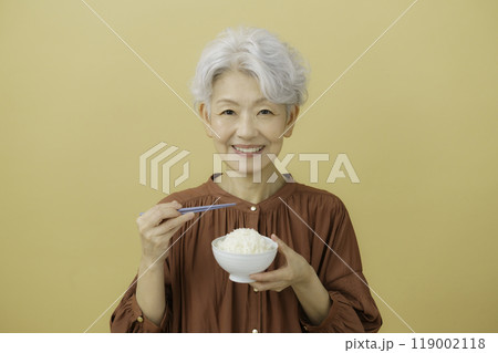 ご飯の入ったお茶碗と箸を持つ白髪のシニア女性 ご飯の入ったお茶碗と箸を持つ白髪のシニア女性 119002118