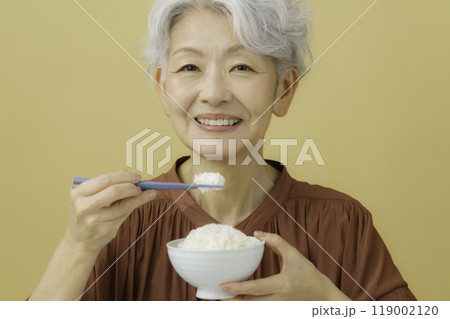 ご飯の入ったお茶碗と箸を持つ白髪のシニア女性 119002120