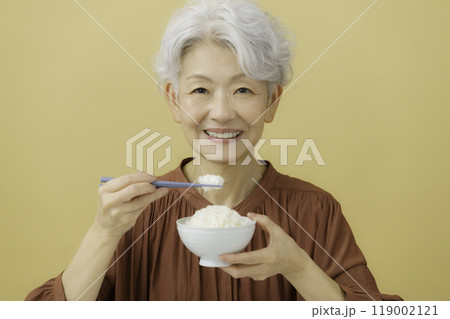 ご飯の入ったお茶碗と箸を持つ白髪のシニア女性 119002121