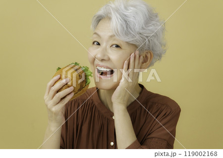 カツバーガーを持つ白髪のシニア女性 119002168