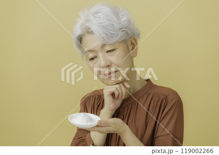 塩を手に持って考える白髪のシニア女性 塩を手に持って考える白髪のシニア女性 119002266