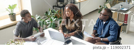 Website banner of young African American team of developers sitting at white table with laptops and having business meeting 119002371