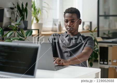 African American programmer writing codes in modern office of famous IT company 119002688