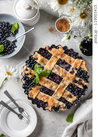Sweet Homemade Blueberry Pie on light kitchen table background with summer flowers top view, flatly 119003415