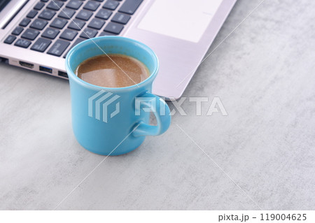 オフィスでデスクワークの合間に、牛乳をたっぷり入れたコーヒーのカフェ・ラッテを飲む 119004625