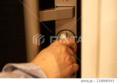 マンションに帰宅して玄関の戸締りをするシニア女性 119006543