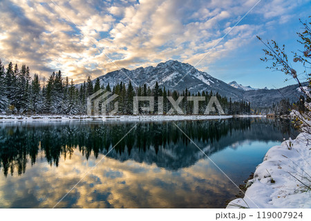 Banff National Park beautiful natural scenery in winter sunset time. Mount Norquay with colourful clouds reflected on Bow River like a mirror. Town of Banff, Canadian Rockies. 119007924