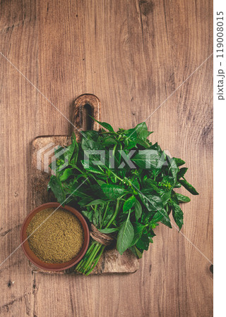 ground green basil, in a ceramic bowl, with a bouquet of fresh green basil, on the table, top view, no people, 119008015