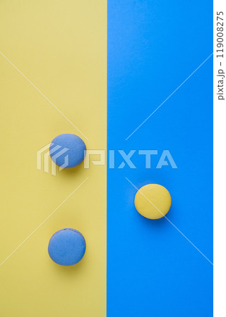 Sweet tasty blue and yellow french macaron cakes on yellow and blue background. Sweet tasty blue and yellow french macaron cakes on yellow and blue background. 119008275