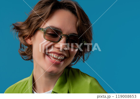 Smiling woman in dark green glasses. Positive stylish lady. Eyewear, sunglasses, fashion accessories. Blue studio background 119008653