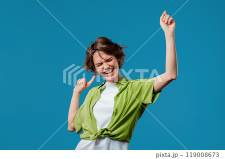 Funny pretty 30s aged woman having fun, favorite music, smiling, dancing on blue studio background. Music, dance concept Funny pretty 30s aged woman having fun, favorite music, smiling, dancing on blue studio background. Music, dance concept 119008673
