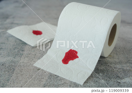 A blood spot is noticeable on a tissue next to a roll of toilet paper in the background A blood spot is noticeable on a tissue next to a roll of toilet paper in the background 119009339