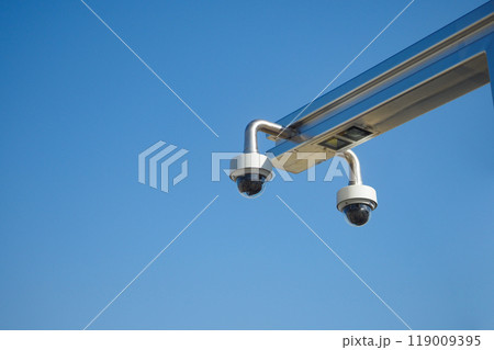 Surveillance Cameras Positioned Against a Clear Blue Sky on a Bright Day of Activities Surveillance Cameras Positioned Against a Clear Blue Sky on a Bright Day of Activities 119009395