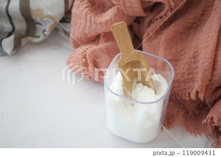 Baking soda in a container and cloths on table  119009431