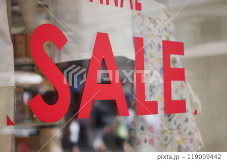 Large red Sale text letters on a glass wall obstruct a view inside the popular fashion store Large red Sale text letters on a glass wall obstruct a view inside the popular fashion store 119009442