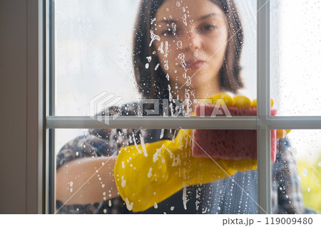 Woman washes the windows with a detergent. 119009480